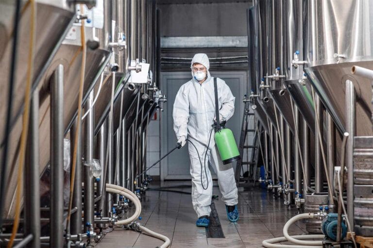 Technician treating a factory floor for commercial pest control