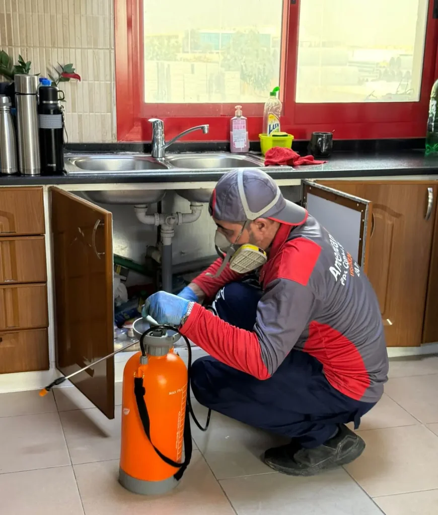 american bite pest control technician removing cockroches in kitchen