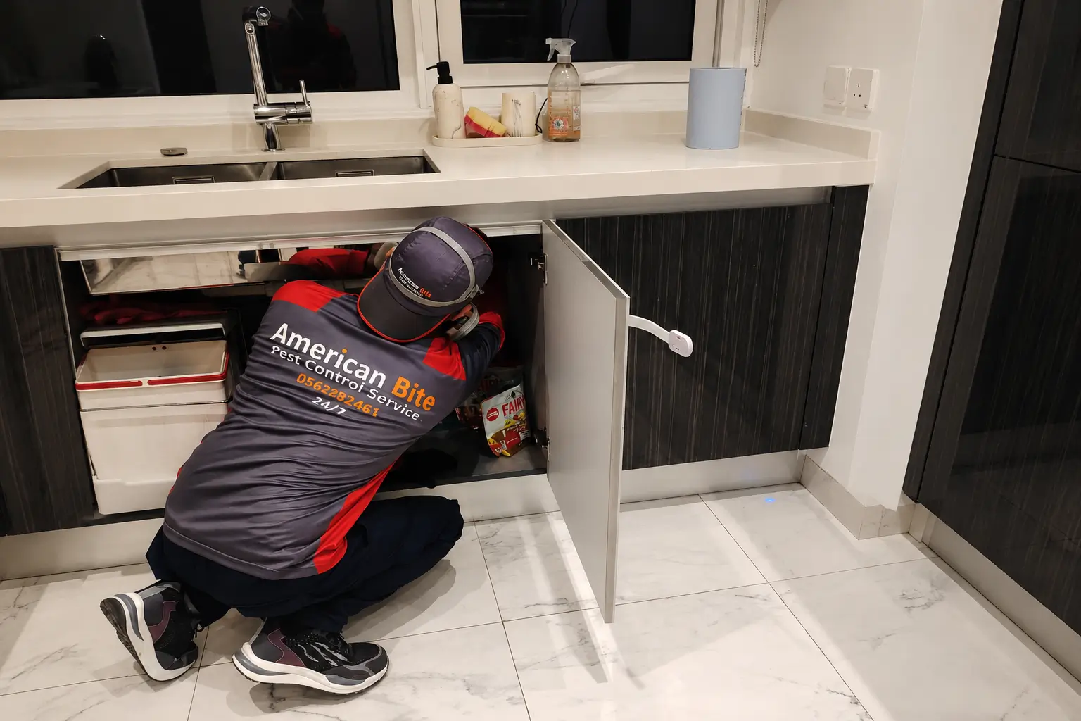 Worker inspecting sink under cabinet (2) (1)