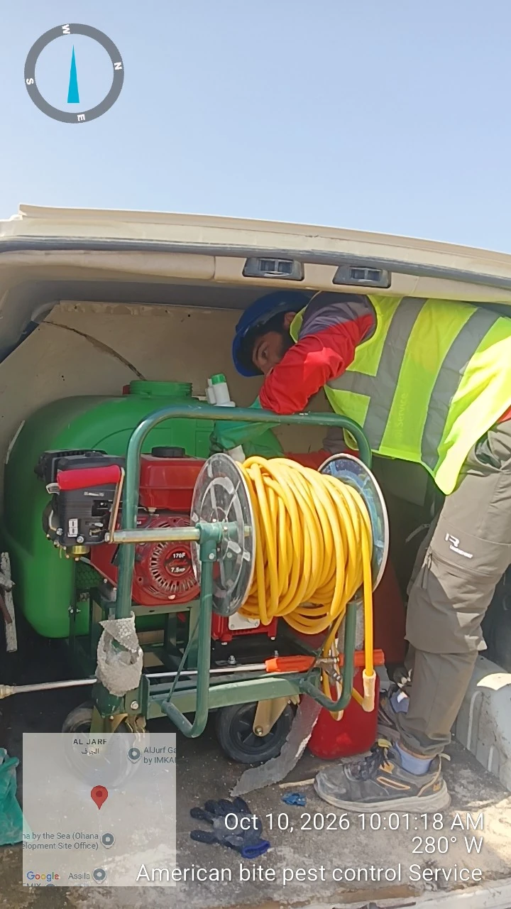 American Bite technician preparing a power sprayer and hose reel for liquid soil barrier termite treatment in Abu Dhabi