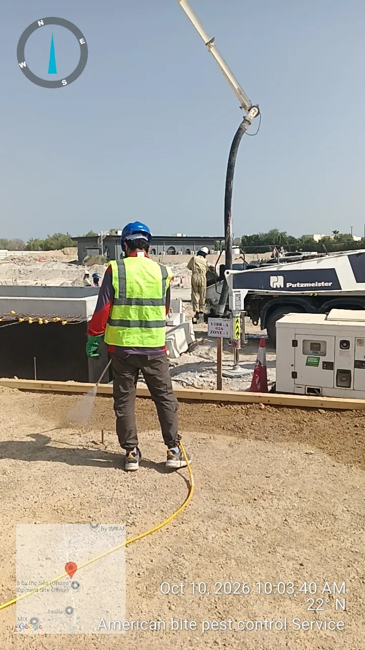 Technician treating the soil beside a concrete foundation to protect a new building from termites in Abu Dhabi